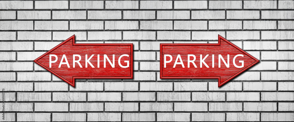 Fototapeta premium Red wooden arrow signs with the inscription PARKING hang on a white brick wall. Right and left arrow pointers. Set direction