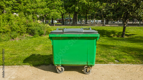 Bright green waste container in a sunlit urban park setting, symbolizing environmental conservation and cleanliness, suitable for Earth Day and public service campaigns