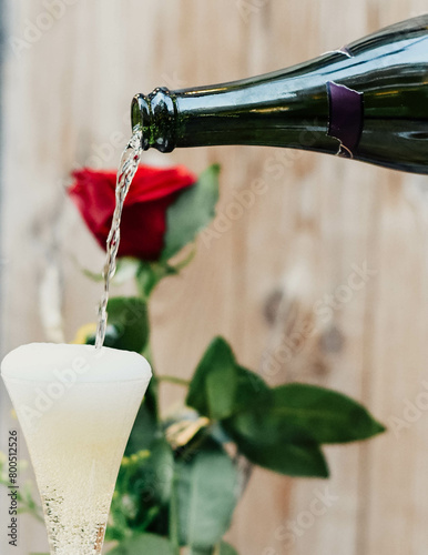 Una rosa roja acompañada de una copa de champagne