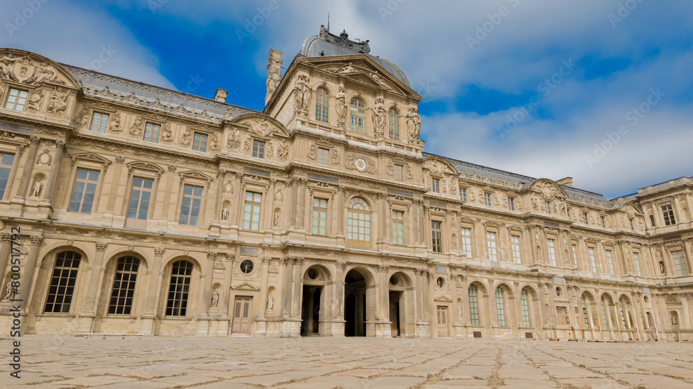 Classical French architecture of the Louvre Museum under a blue sky, ideal for travel, tourism, and European heritage concepts