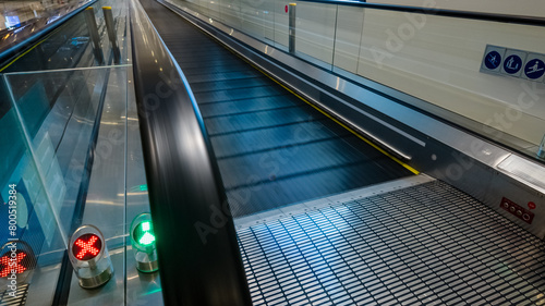 Modern airport travelator with red and green safety lights and motion blur, conveying concepts of transport, technology, and travel efficiency