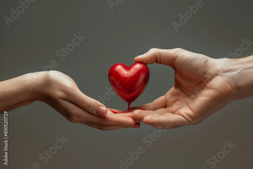 close-up of two pairs of hands, one extending to give blood and the other receiving it. Symbolically giving blood from one person to another. Also concept image for World blood donor day - June 14.  photo