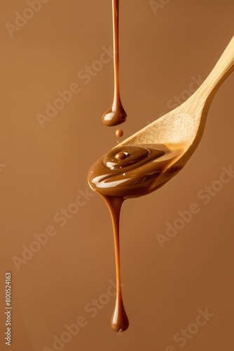 Wallpaper Mural liquid chocolate dropping from a wooden spoon isolated on a light brown background Torontodigital.ca