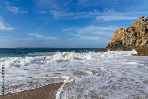 Le sable de la plage recouvert d'écume blanche, avec une falaise en bout de plage, une scène typique de la mer d'Iroise en Bretagne, où terre et mer se rencontrent dans une harmonie naturelle photo