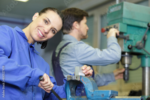 man and woman using machinery in industrial factory