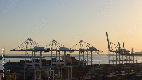 High angle drone shot of cargo containers and huge cranes at commercial dock by sea against clear sky at Miami port in Florida