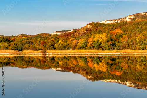 Colorful mountain reflection on a calm lake at sunrise during autumn.