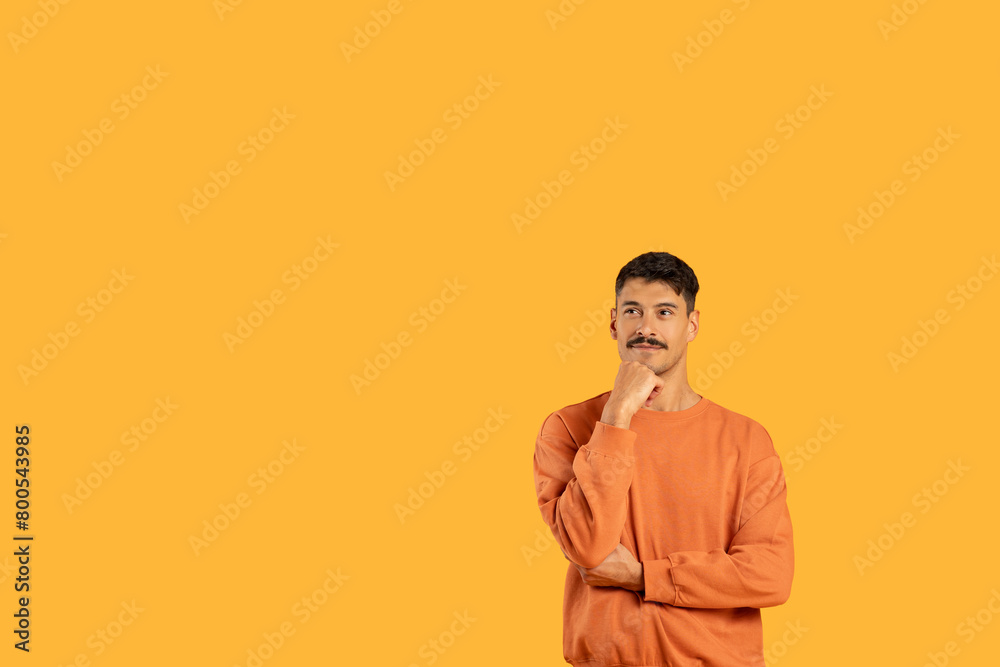 Man in Orange Shirt Standing With Hand on Chin