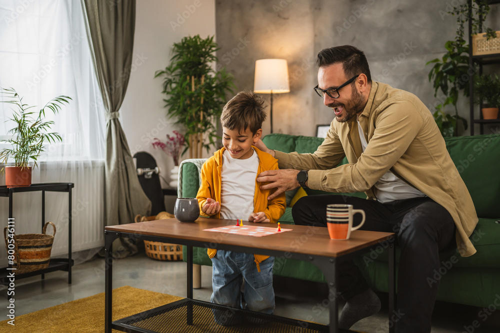 Father and son play board game together at home