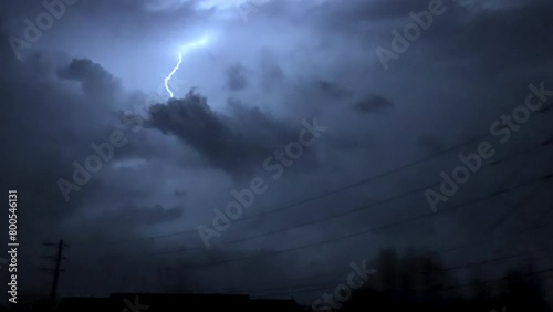 Low angle tracking shot of electricity pylon against stormy sky with lightning at night