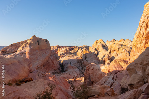 Panoramic sunrise view of arid landscape with striated red and white rock formations along the White Domes Hiking Trail in Valley of Fire State Park in Mojave desert, Overton, Nevada, USA. Road trip