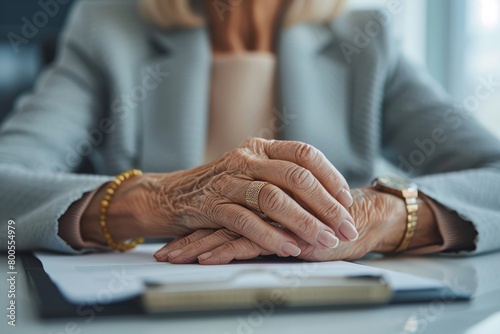 A close-up photo of the hands of a senior businesswoman sitting in the office at a desk  massaging her tired hand  Generative AI