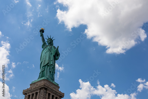 A close up on an iconic representation of freedom and independence  the Statue of Liberty with flaming torch on Liberty Island. The Lady on a Pedestal is surrounded by clouds. American history.