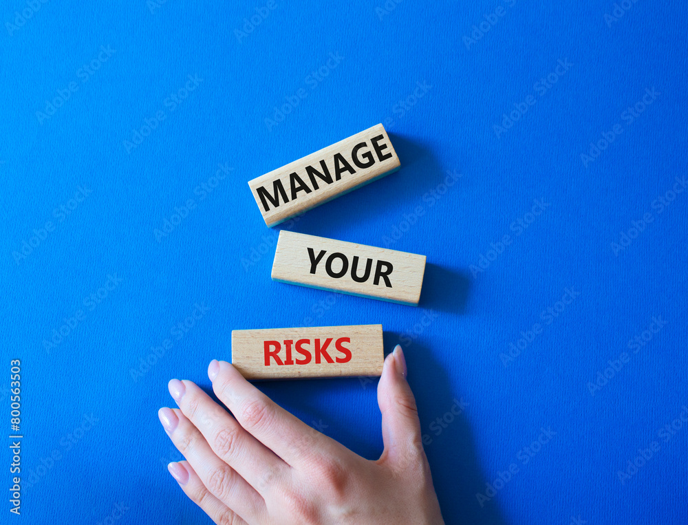 Manage your Risks symbol. Concept words Manage your Risks on wooden blocks. Businessman hand. Beautiful blue background. Business and Manage your Risks concept. Copy space. Manage your Risks symbol. Concept words Manage your Risks on wooden blocks. Businessman hand. Beautiful blue background. Business and Manage your Risks concept. Copy space.