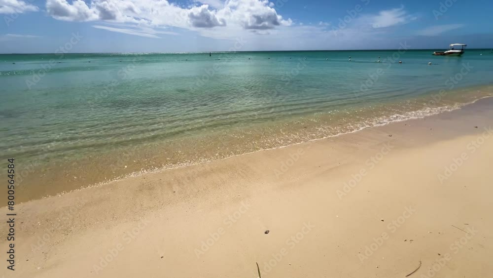 Cloudy blue sky and The turquoise crystal waters of the ocean hit the sand on the beach. Mauritius island in the Indian ocean Cloudy blue sky and The turquoise crystal waters of the ocean hit the sand on the beach. Mauritius island in the Indian ocean