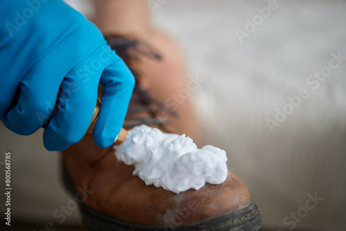 Applying cleaning foam from the bottle to white leather women s sneakers. Care for leather shoes  surface whitening.