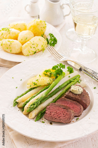 Traditional roasted angus beef steak with white and green asparagus, boild potatoes and sauce hollandaise served as close-up on a classic plate