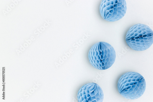 Small tissue paper balls scattered on a blue background. Festive decorations. Place for text.
