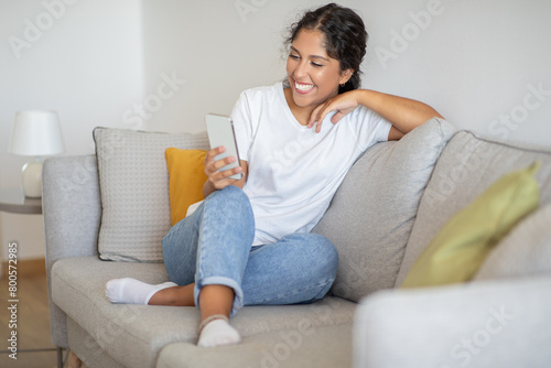 Woman Sitting on Couch Smiling at Cell Phone