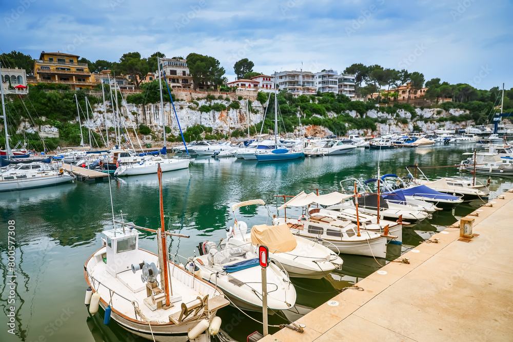 Obraz premium A serene view of the Porto Cristo harbor in Mallorca, showcasing moored boats and the surrounding landscape