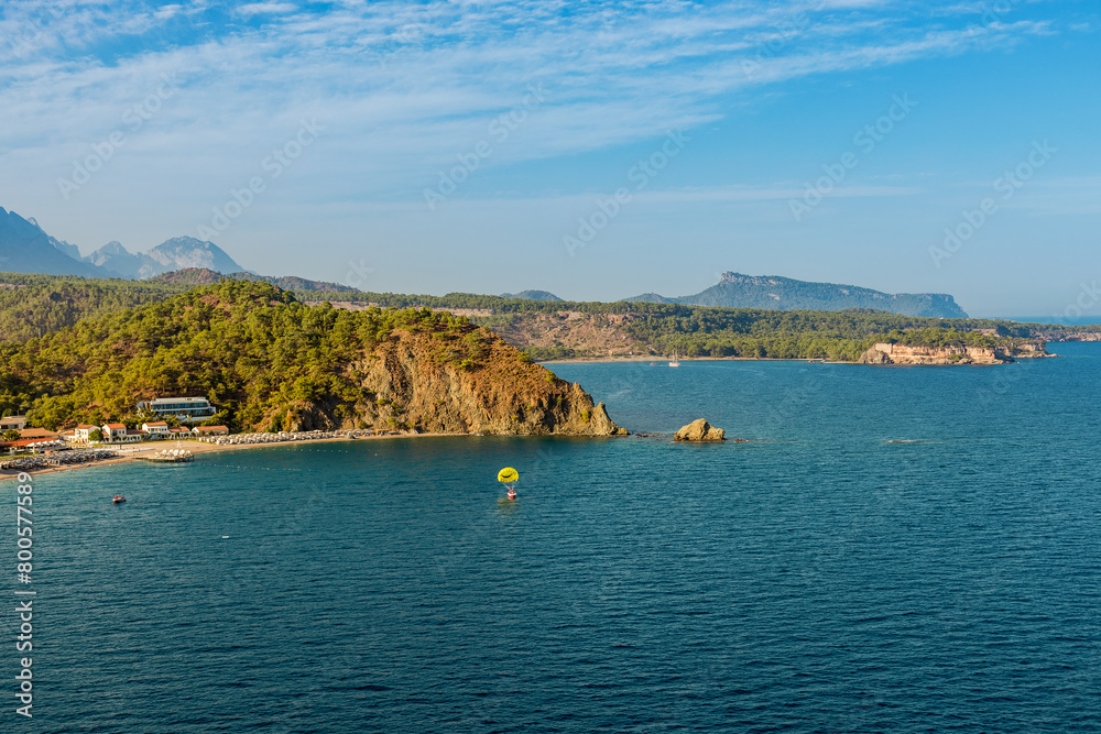 The beauty of a Turkish seaside, where the calm sea meets the lush peninsula adorned with verdant foliage. Majestic mountains rise in the background