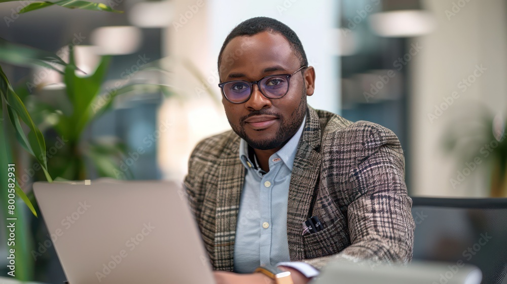 Well-dressed Afro-Caribbean businessman using a laptop with a thoughtful expression Well-dressed Afro-Caribbean businessman using a laptop with a thoughtful expression