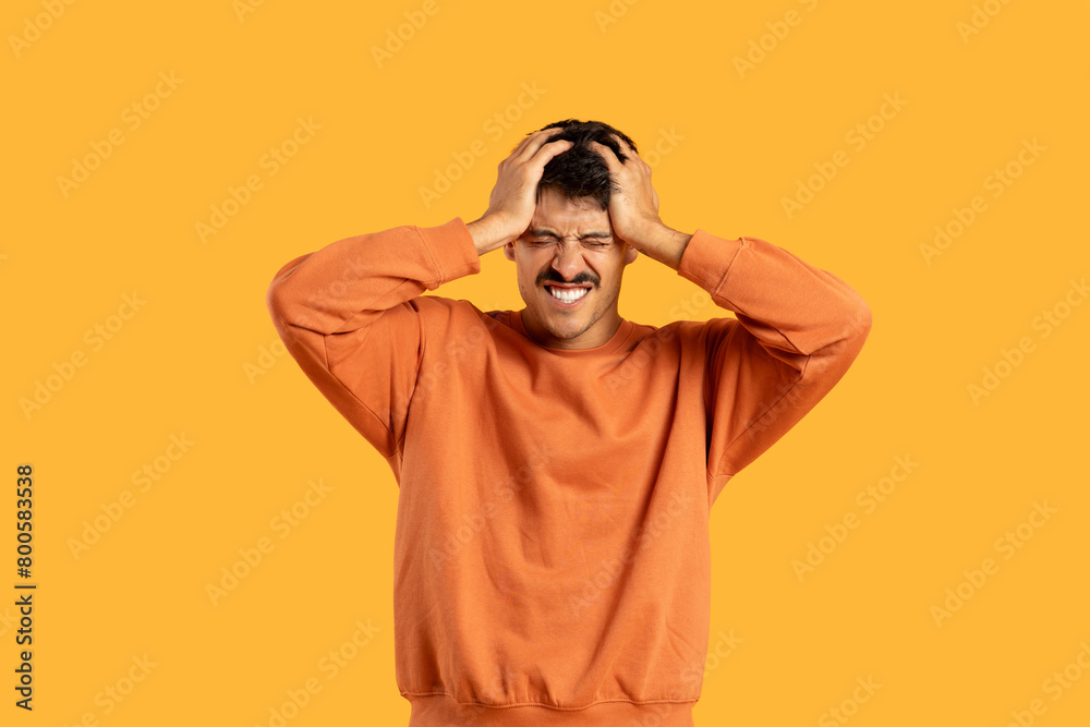 Man in Orange Shirt Holding Head In Despair
