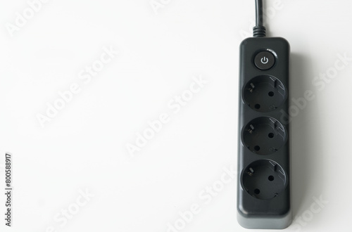 Electrical extension cord, with three outlets, power button and contacts for safe grounding. Powerful, with thick black wire. White background. Photo. Copy space