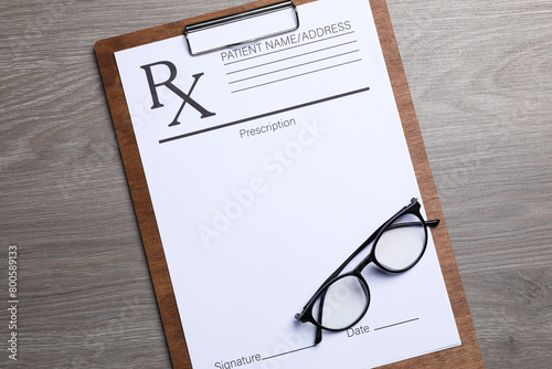 Foto Clipboard with medical prescription form and glasses on wooden table, top view