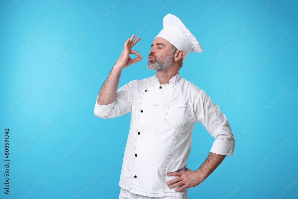 Naklejka premium Chef in uniform showing perfect sign on light blue background