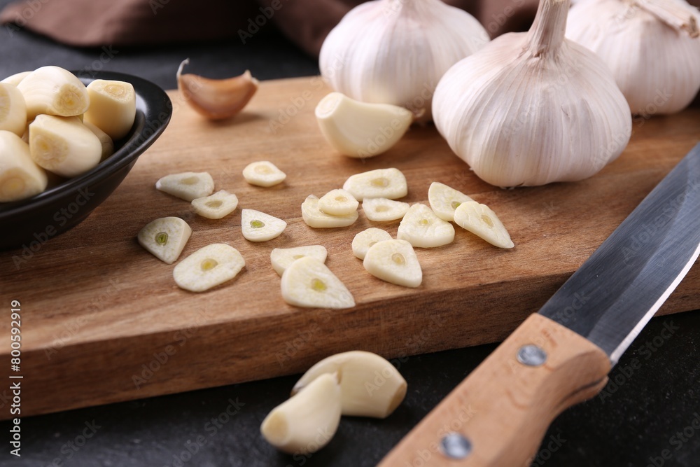 Aromatic cut garlic, cloves, bulbs and knife on dark table, closeup Aromatic cut garlic, cloves, bulbs and knife on dark table, closeup