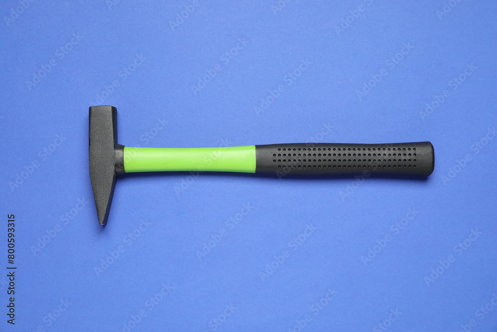 New hammer with rubber handle on blue background, top view New hammer with rubber handle on blue background, top view