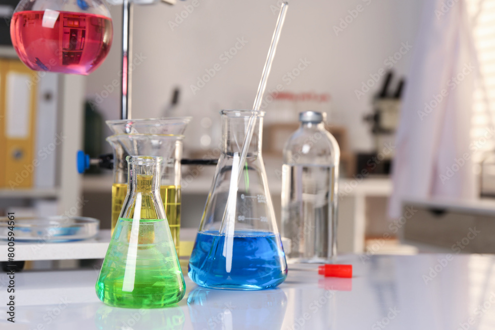 Laboratory analysis. Glassware with different liquids on white table indoors Laboratory analysis. Glassware with different liquids on white table indoors