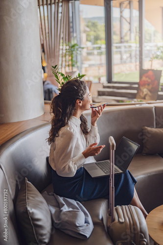 Businesswoman sitting in a hotel lobby, using laptop. Woman working on a business trip using online connections. Business lady went to business trip and stayed at the hotel.