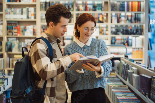 A young man and woman explore a selection of books in a cozy bookstore. They appear engaged and happy as they discuss their finds among shelves filled with books.