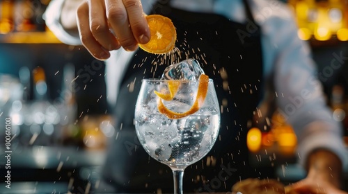 Close-up male bartender sprinkling to glass with cold alcohol cocktail with piece of orange citrus zest photo