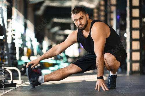 Handsome Millennial Man Squatting on Gym Floor