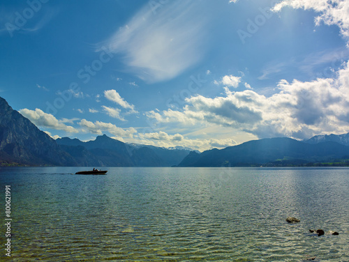 Peaceful spring mountain lake in the Alps. View of Lake Traunsee, pleasure Boat and Mount Traunstein in background. Upper Austria.