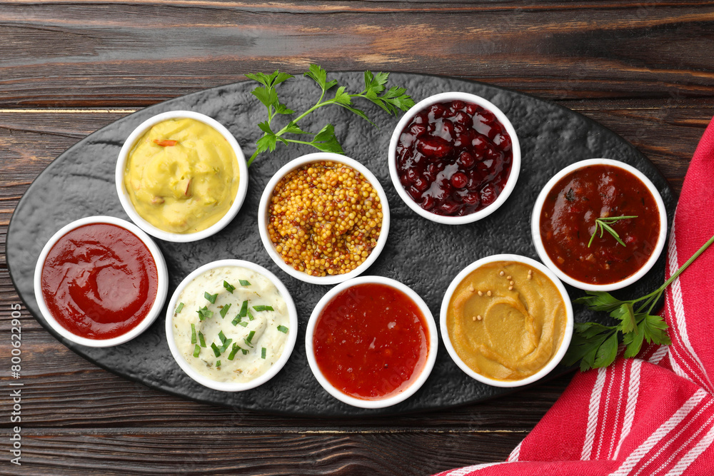 Different tasty sauces in bowls and parsley on wooden table, top view Different tasty sauces in bowls and parsley on wooden table, top view