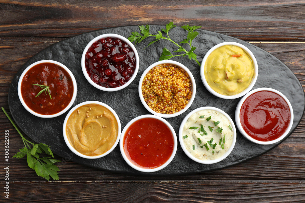 Different tasty sauces in bowls and parsley on wooden table, top view Different tasty sauces in bowls and parsley on wooden table, top view