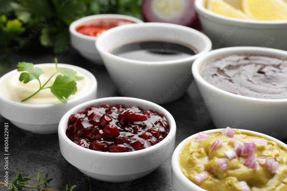 Different tasty sauces in bowls on grey table, closeup Different tasty sauces in bowls on grey table, closeup