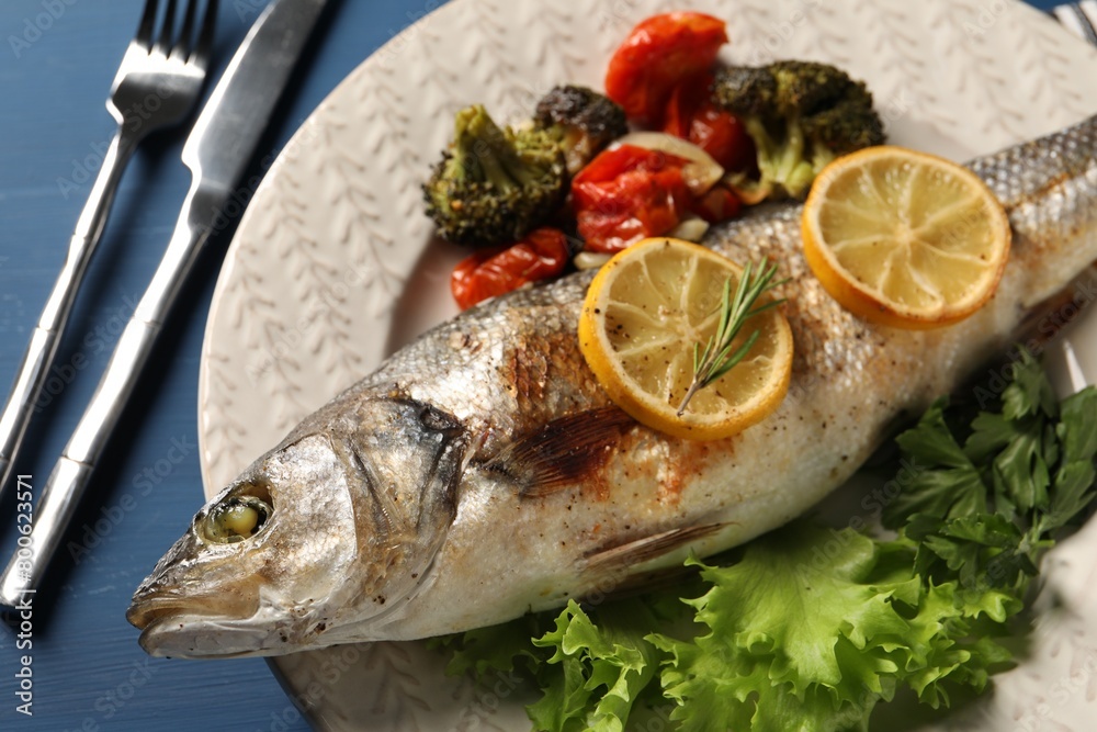 Delicious baked fish and vegetables served on blue wooden table, closeup Delicious baked fish and vegetables served on blue wooden table, closeup
