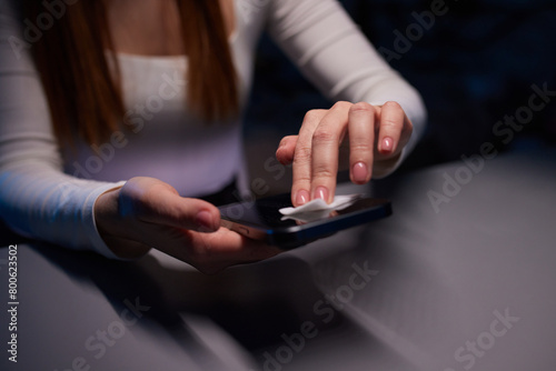 Hand female cleaning her smartphone with microfiber cloth
