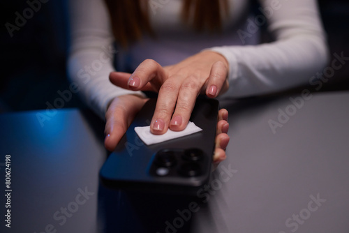 Hand female cleaning her smartphone with microfiber cloth