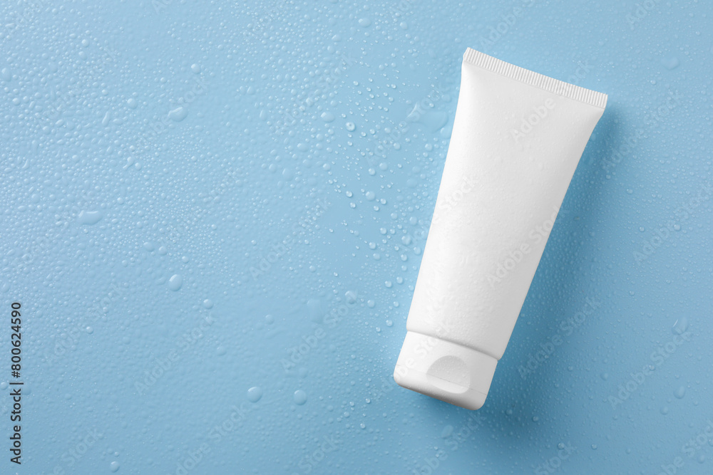 Moisturizing cream in tube on light blue background with water drops, top view. Space for text Moisturizing cream in tube on light blue background with water drops, top view. Space for text