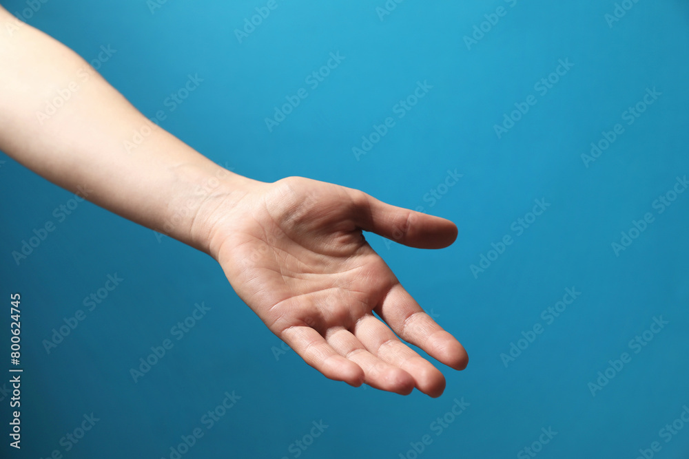 Woman holding something in hand on light blue background, closeup