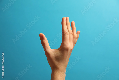 Woman holding something in hand on light blue background, closeup