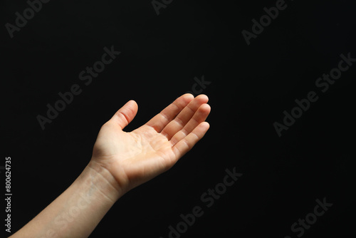 Woman holding something in hand on black background, closeup. Space for text