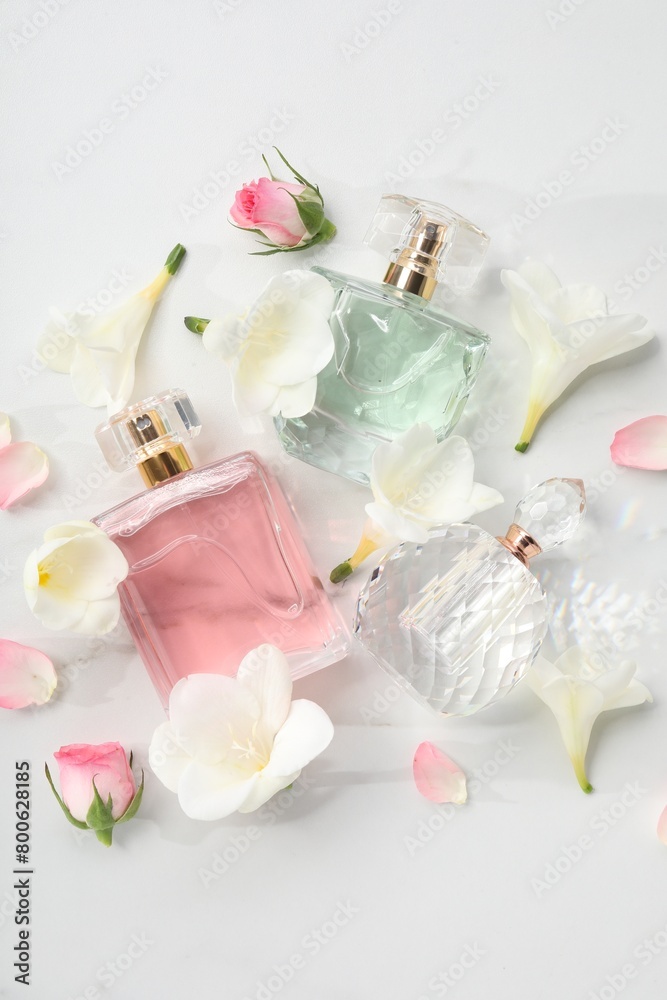 Luxury perfume and floral decor on white marble table, flat lay
