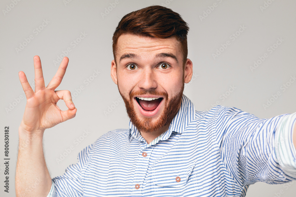 Happy millennial guy showing OK sign on camera Happy millennial guy showing OK sign on camera